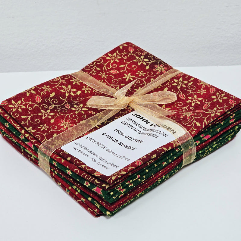 Stack of red and green fabric bundles tied with a gold ribbon on a white background